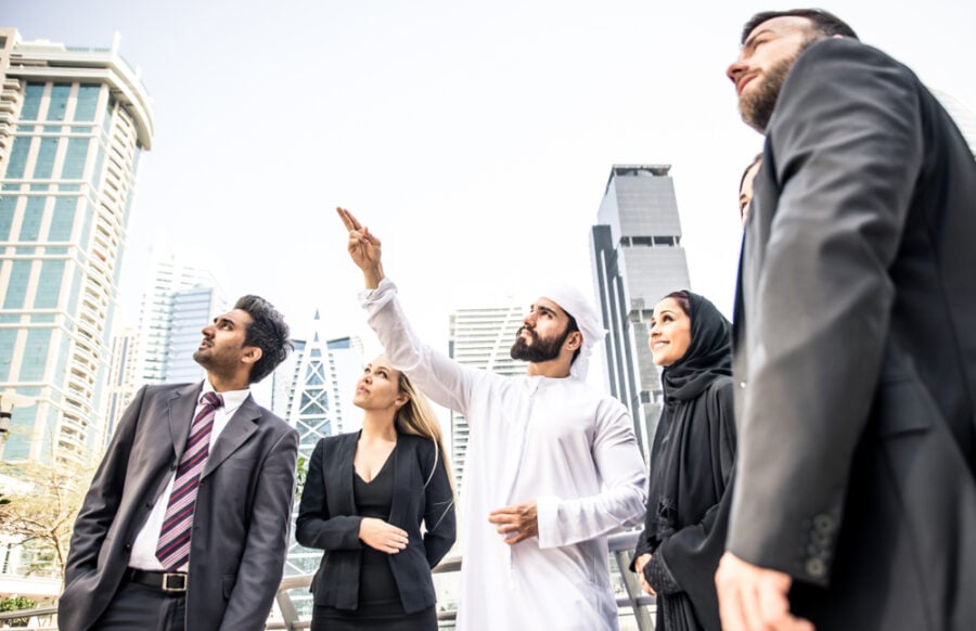 Man in thobe points upwards with business professionals.