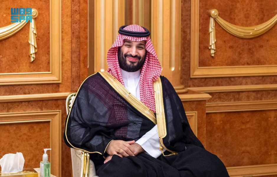 Smiling man in Saudi attire in a wood-paneled room.