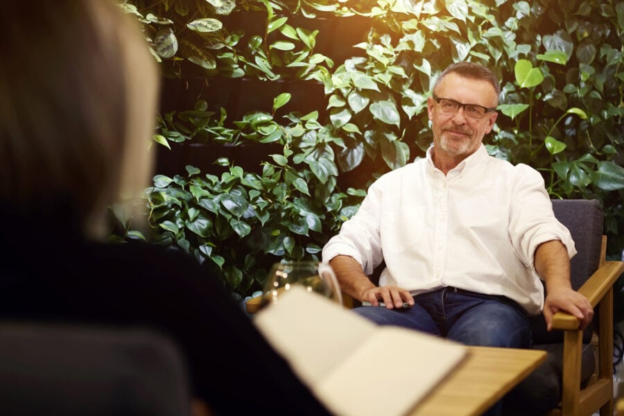 Man smiling in a meeting with a notebook in front.