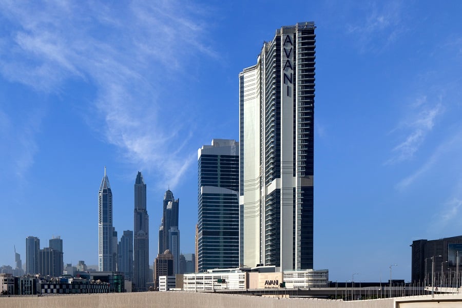 AVANI hotel amidst skyscrapers under a blue sky.