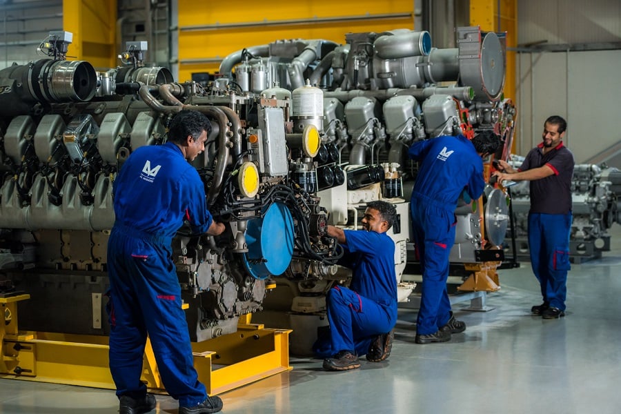 Mechanics repairing an industrial engine in a factory.