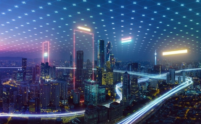 Nighttime cityscape with glowing frames and vehicle light trails.