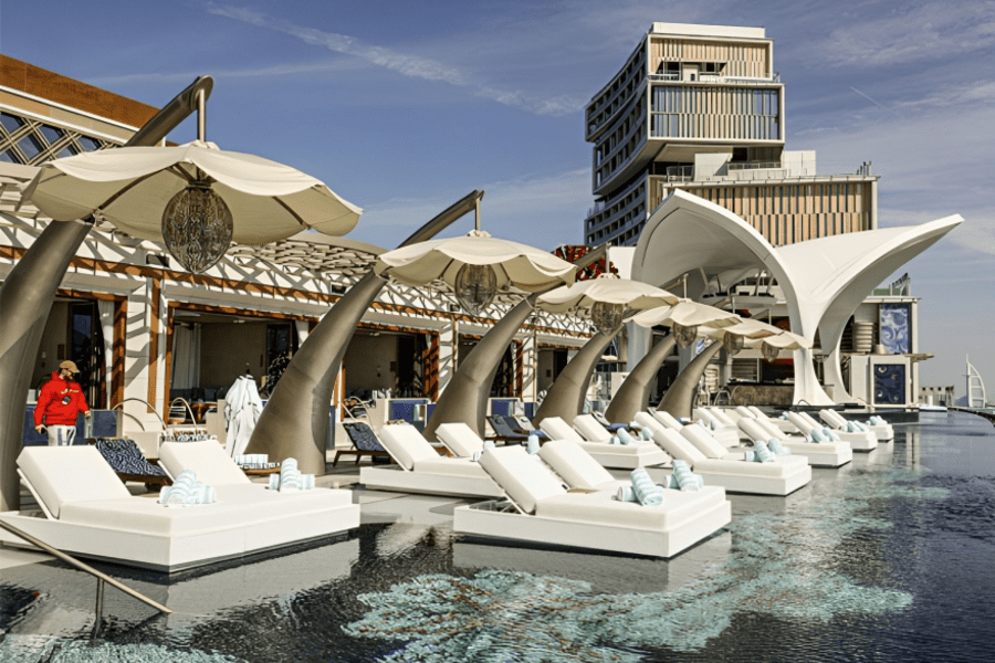 Lounge chairs line infinity pool with umbrellas.