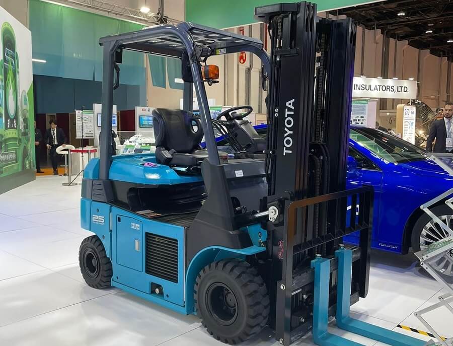 Blue Toyota forklift on display near a blue car.