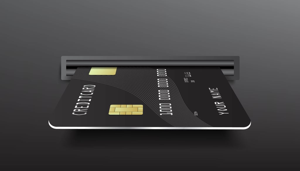 Black credit card being inserted into a gray ATM slot.