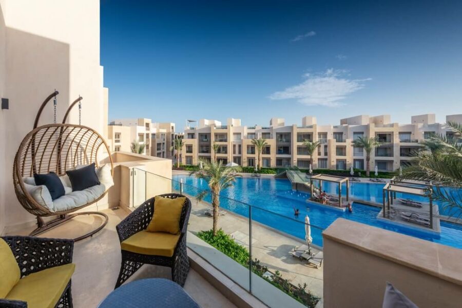 Wicker hanging chair overlooking a swimming pool.