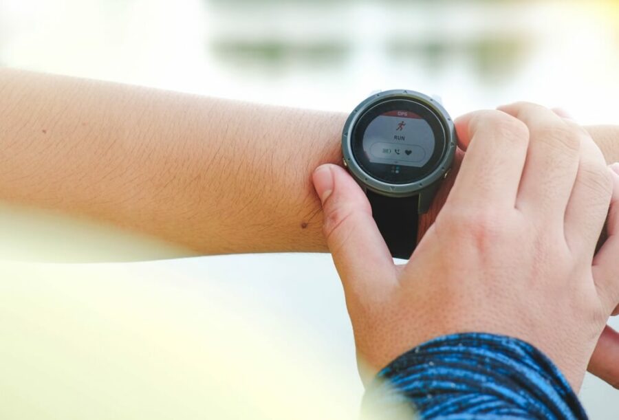 Smartwatch displaying "RUN" and heart rate, with GPS outdoors.