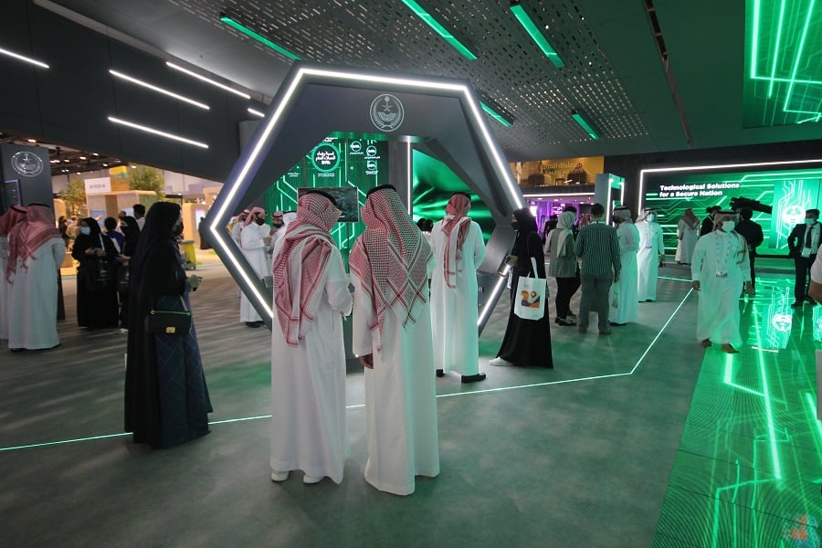 Men in traditional attire interacting with a technological display.
