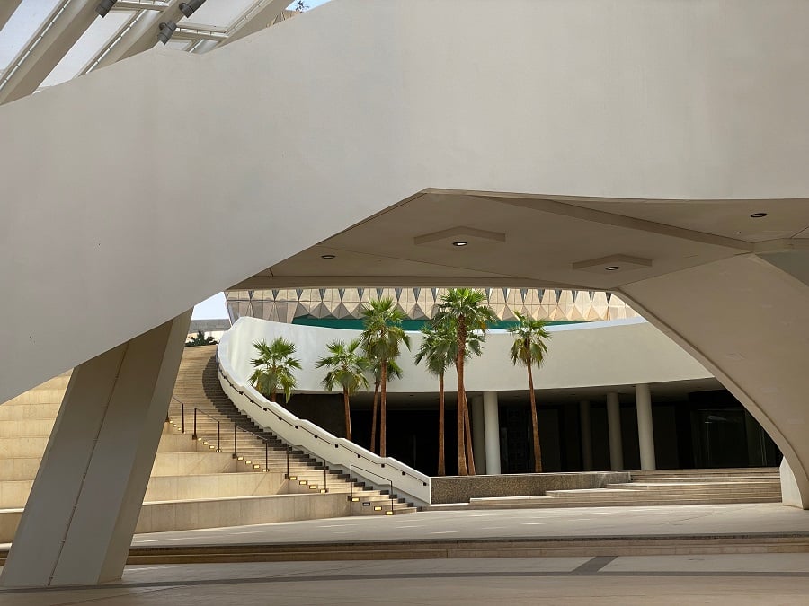 Curved staircase in modern white building with palm trees.