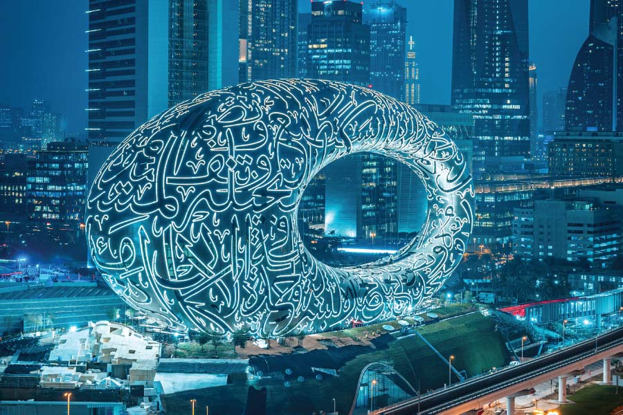 Illuminated Arabic calligraphy ring among modern skyscrapers at night.