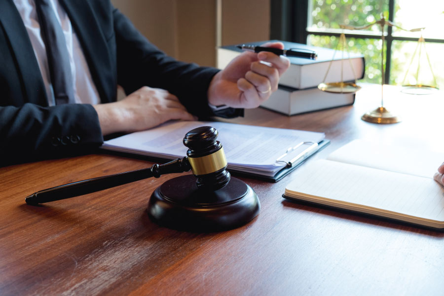Gavel on a wooden table with legal documents and a scale of justice.