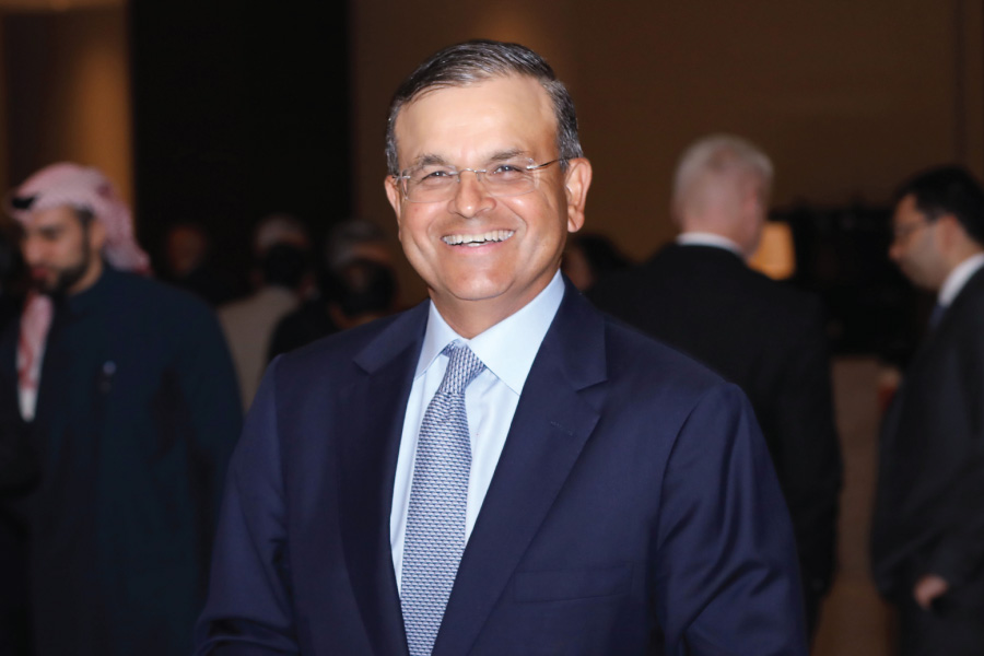 Man in a navy suit smiling at an indoor event.
