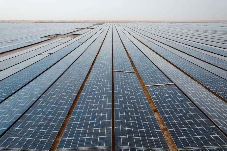 Solar panels in rows across a desert-like landscape.