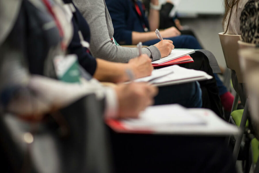 People writing in notebooks during a conference.