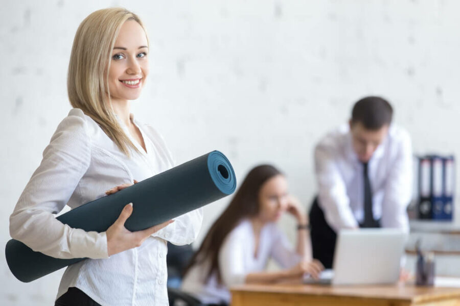 Woman with yoga mat in an office.
