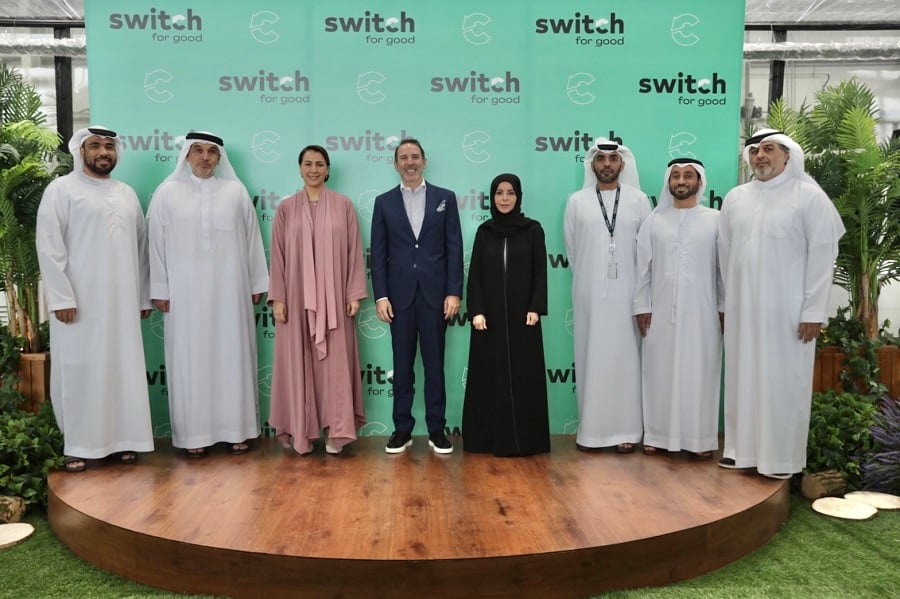 Group of eight posing in front of a "switch for good" banner.