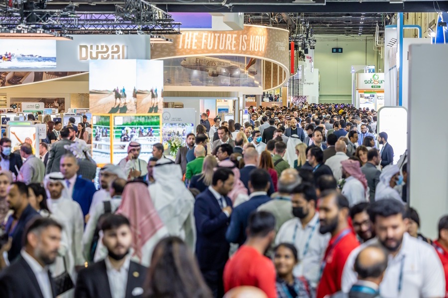 Crowd at a convention center with "THE FUTURE IS NOW" and "DUBAI" signs.