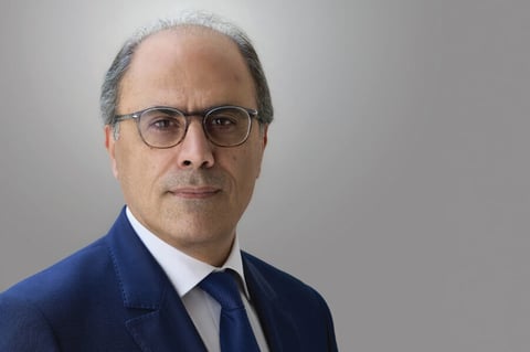 Man in glasses and suit against a grey background.
