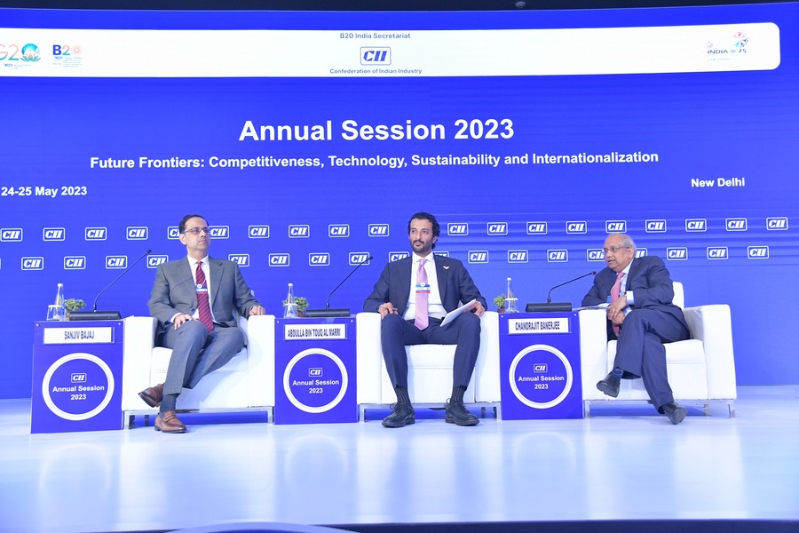 Three men discussing competitiveness and sustainability at an event.