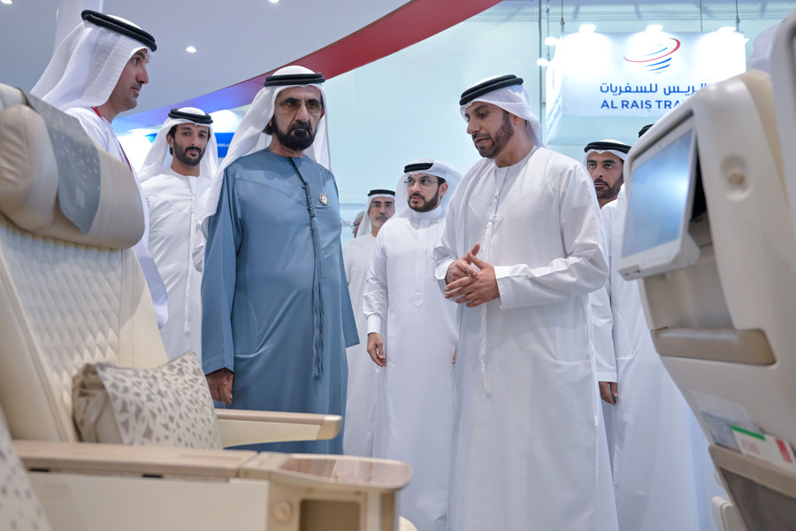 Emirati men inspecting an airplane seat at an exhibition.