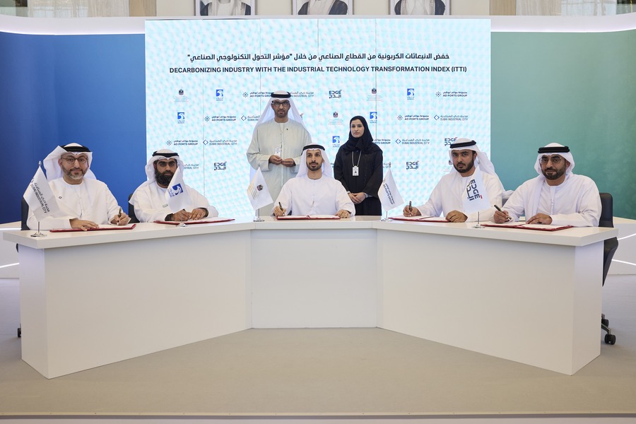 Emirati men signing documents at an official event.