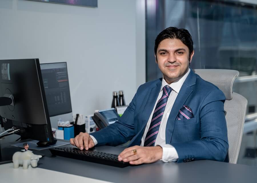 Man in blue suit working at a computer in an office.