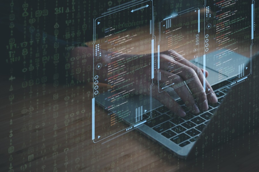 Hands typing on a laptop with lines of code overlay.