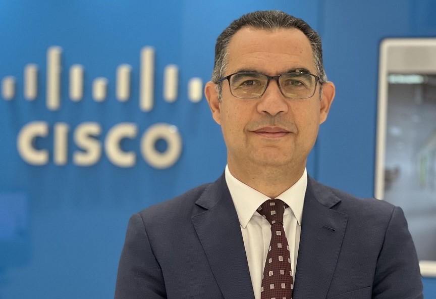 Man in suit posing by Cisco logo.