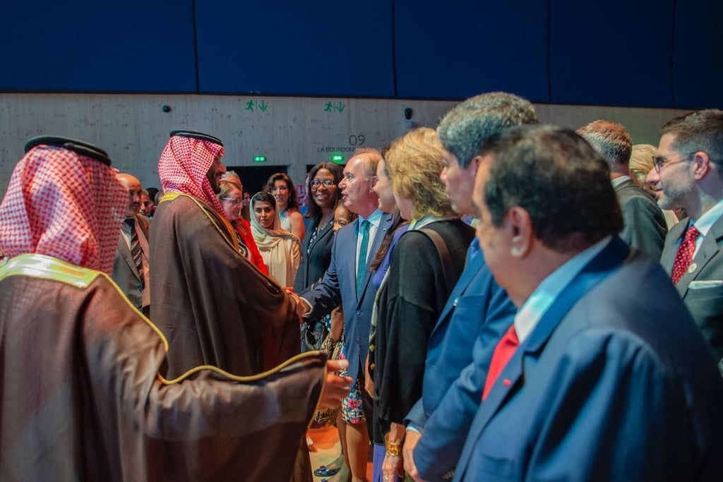 Men in Saudi and formal attire shake hands at an event.