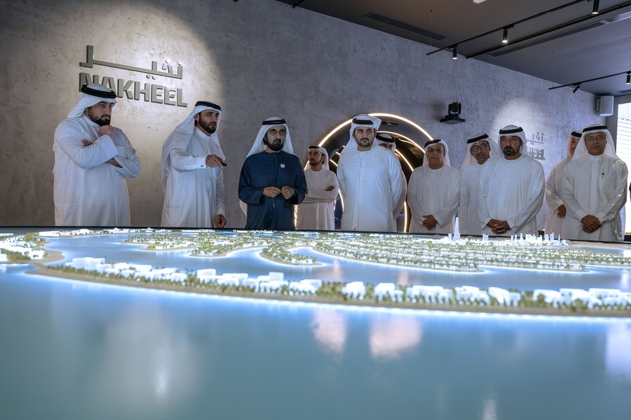 Island model being observed by men in traditional robes.