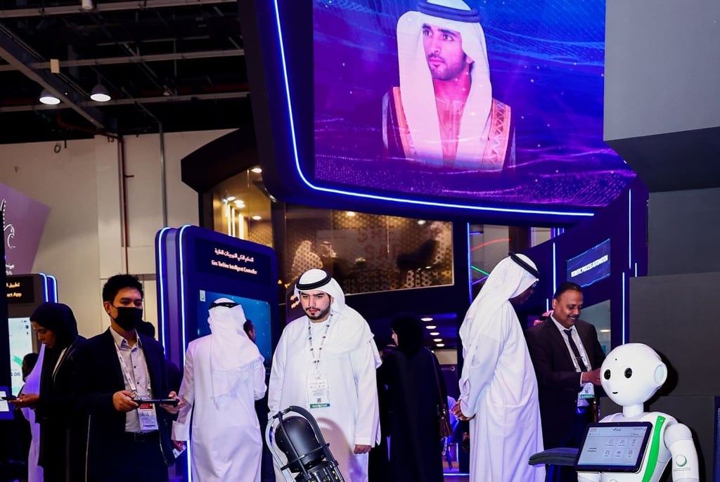 People in traditional attire at a tech expo with interactive displays and a robot.