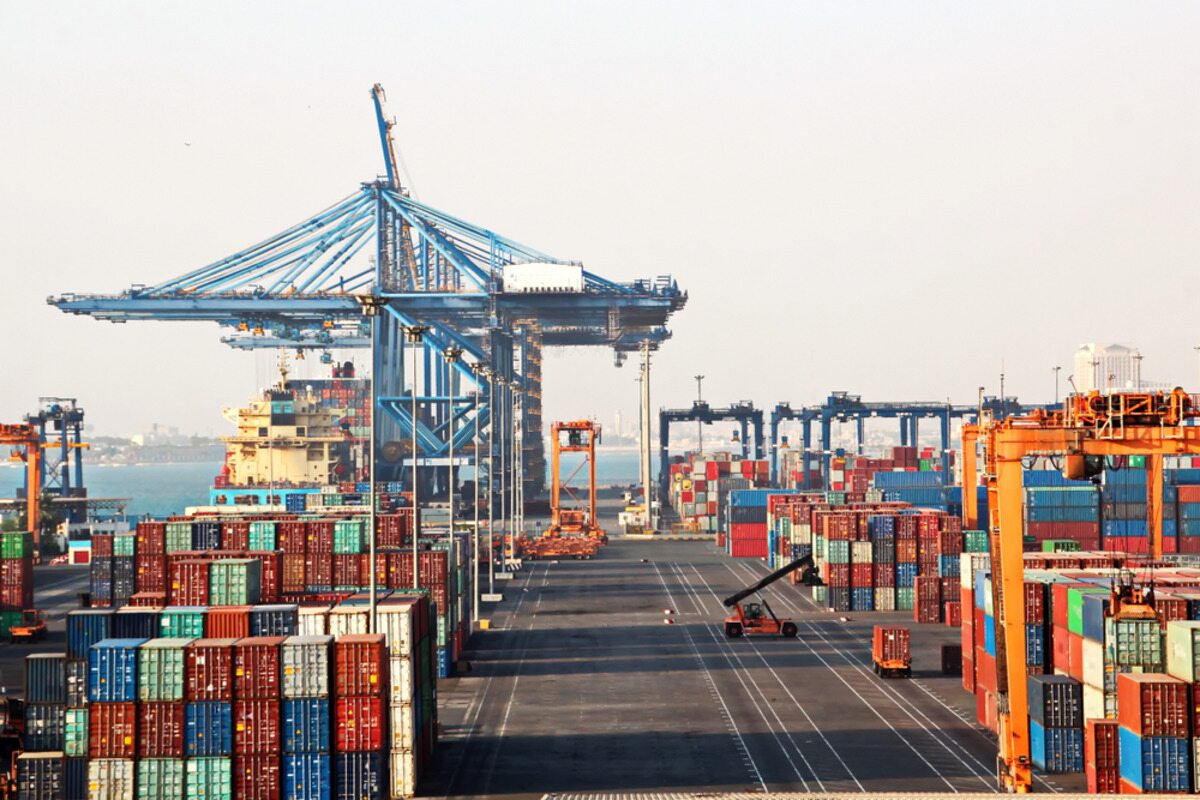 Cargo containers being loaded at a busy port with cranes.