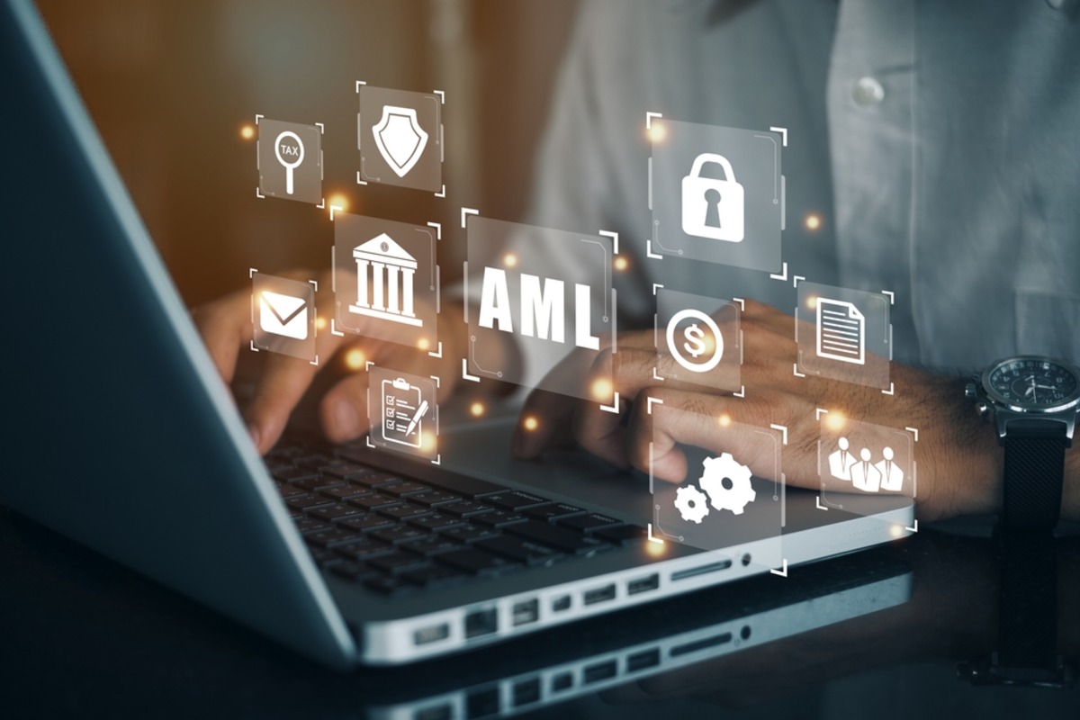 Hands typing on a laptop displaying AML compliance icons.