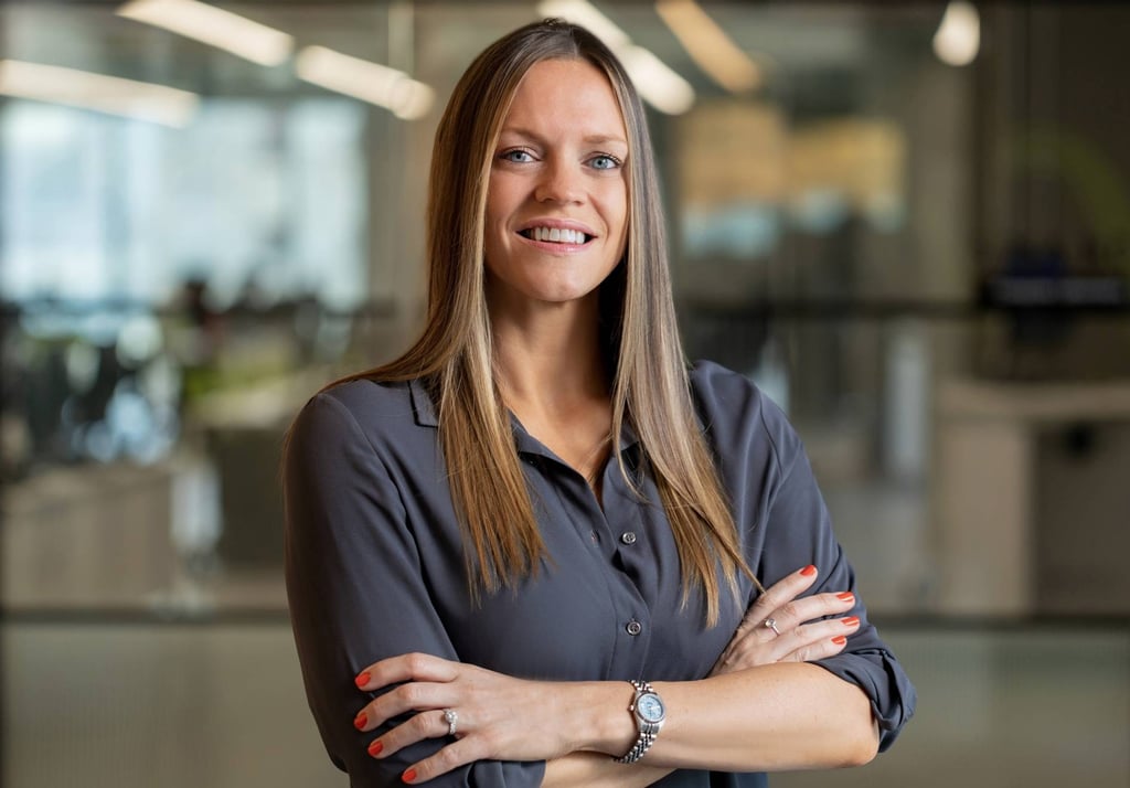 Smiling woman with arms crossed in an office.