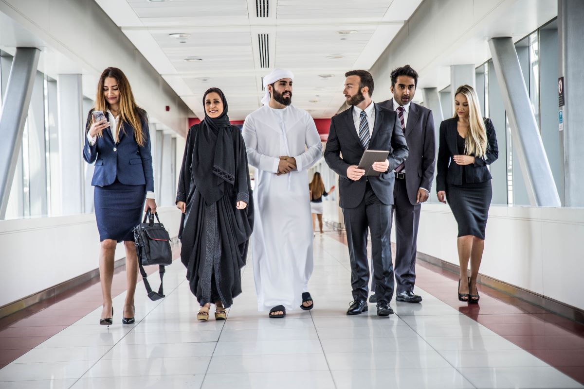 Businesspeople walking down a hallway, some on phones or with briefcases.