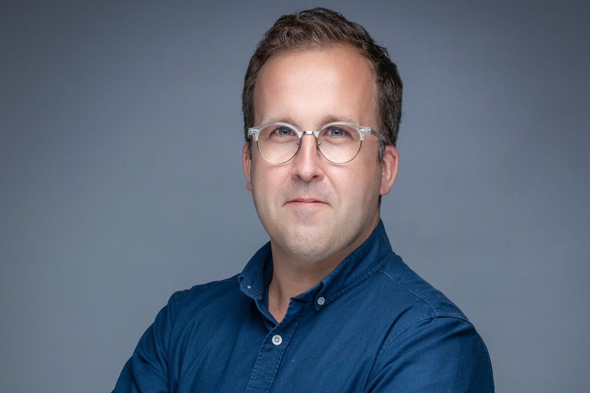 Man in glasses and blue shirt with arms crossed.