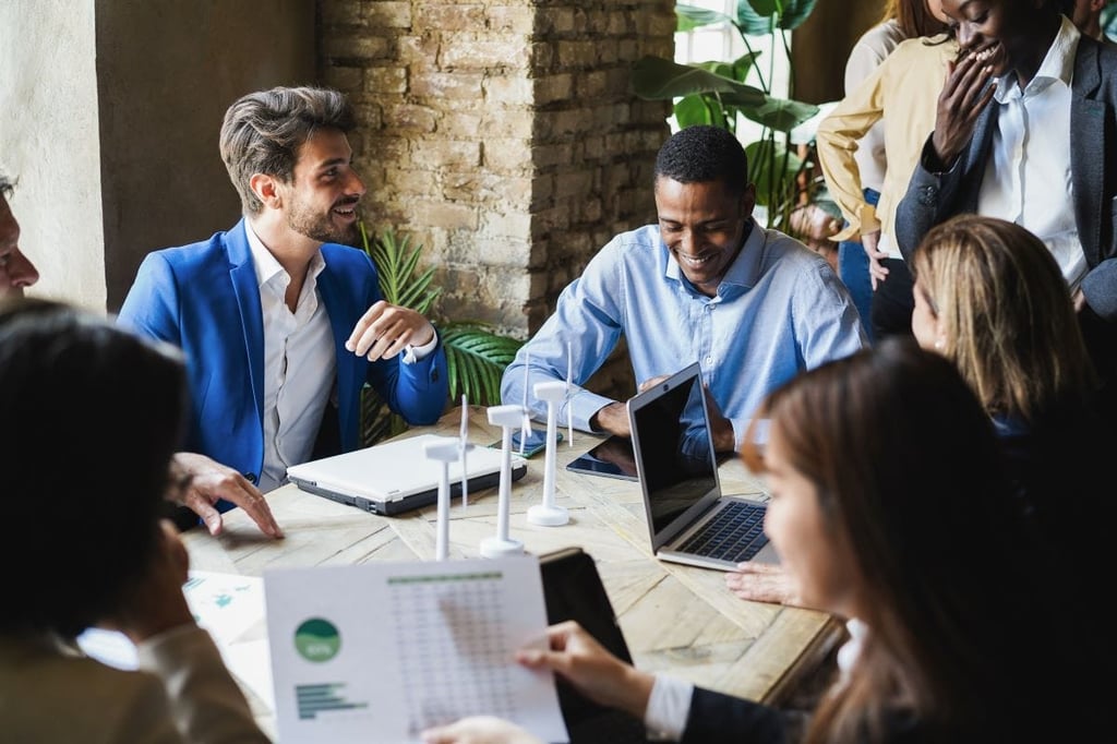 Businesspeople collaborating around a table with wind turbines.