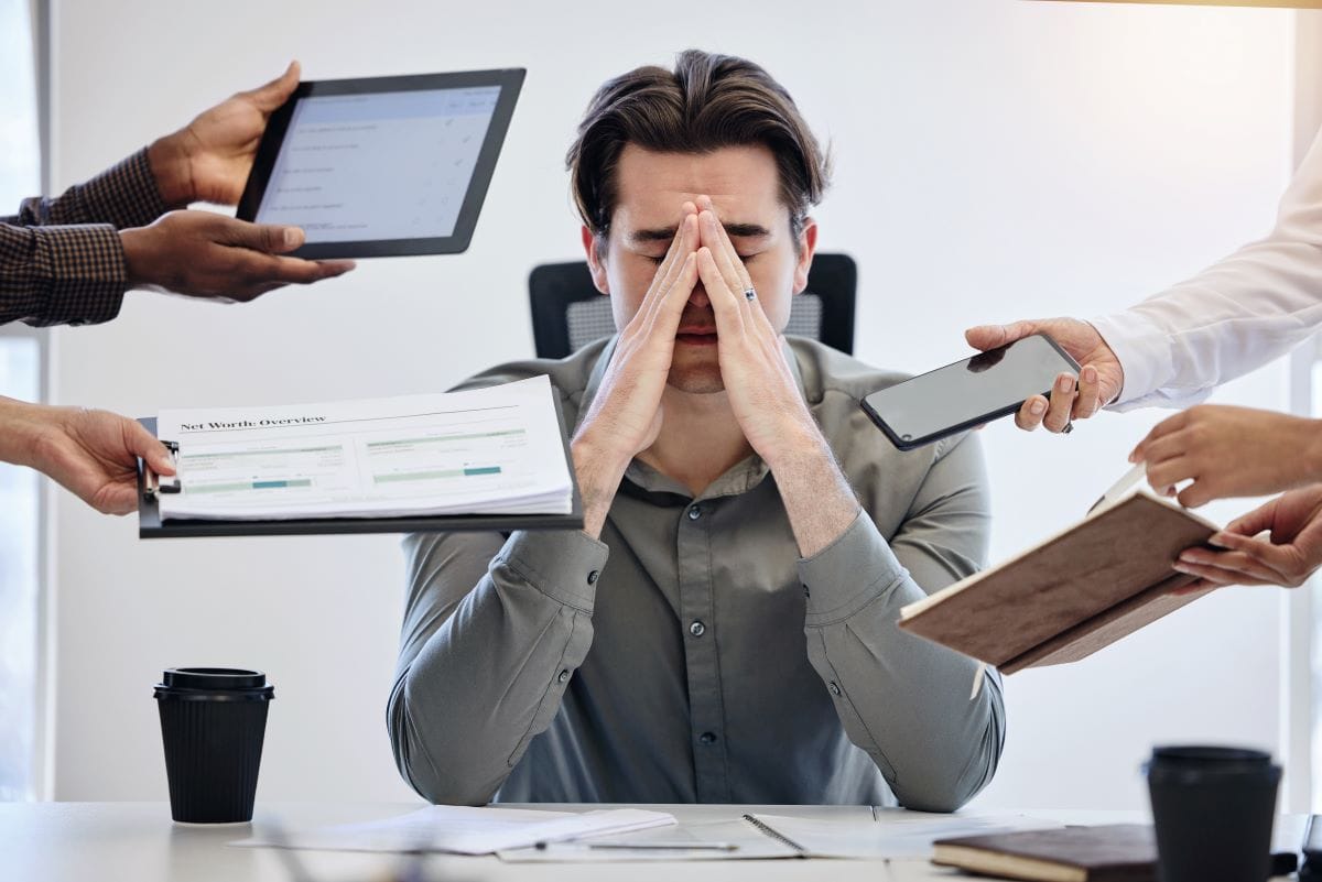 Man stressed at desk surrounded by work documents.
