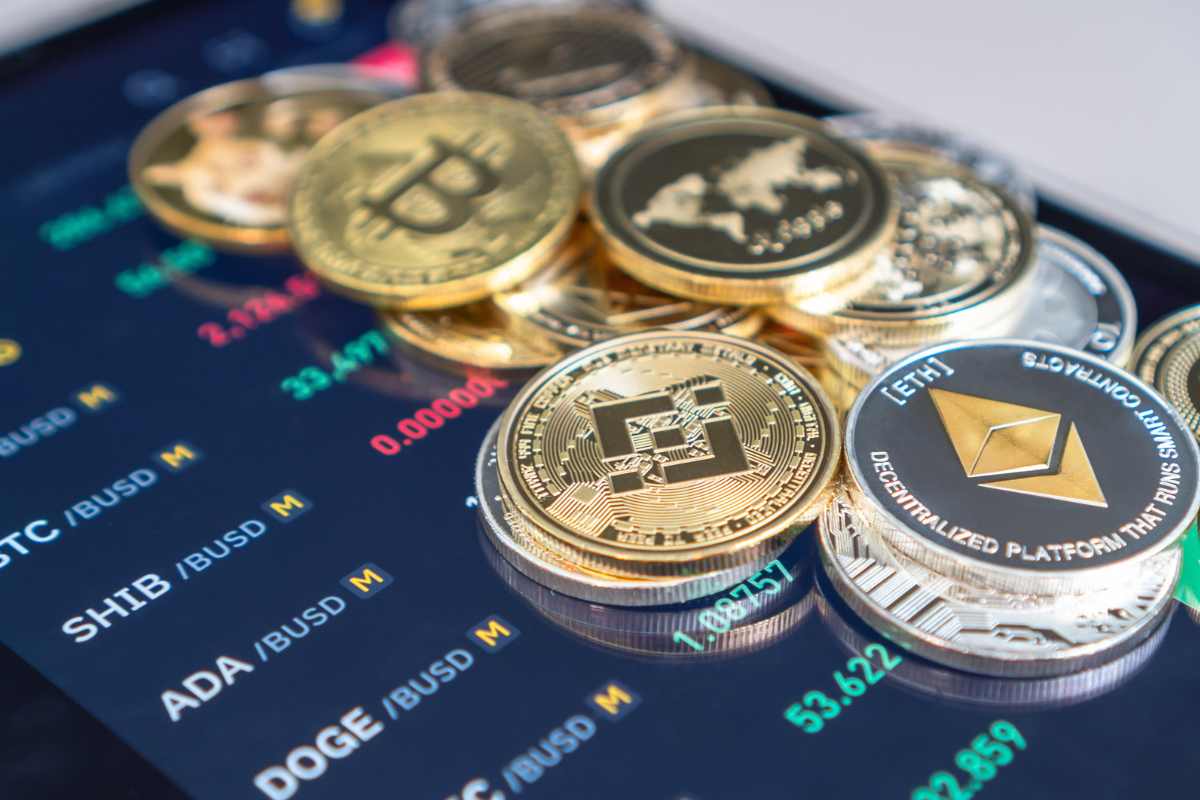 Cryptocurrency coins rest on a screen displaying market prices.