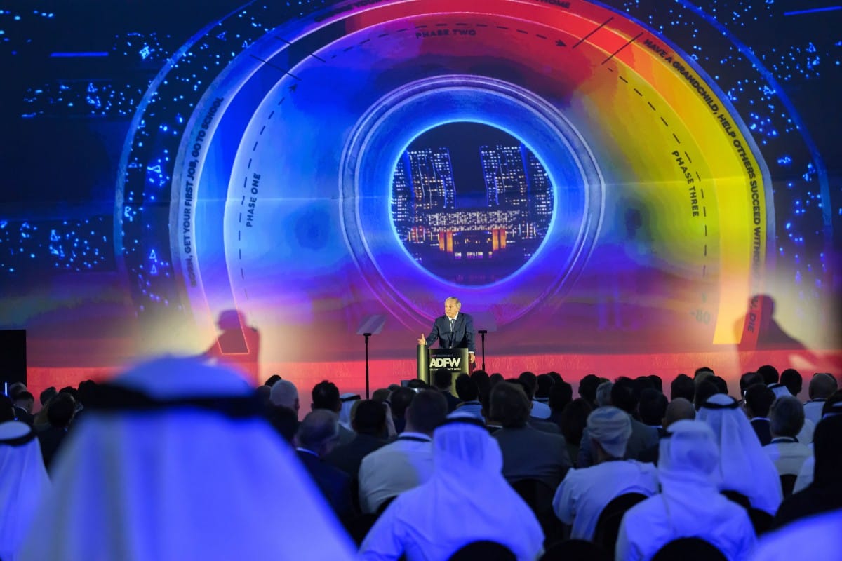 Man delivering a speech with a life phases graphic behind him.
