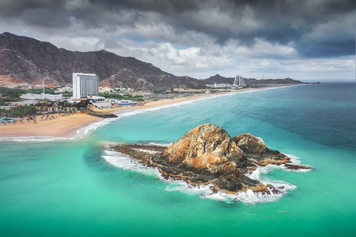 Rocky islet surrounded by turquoise water and sandy beach.