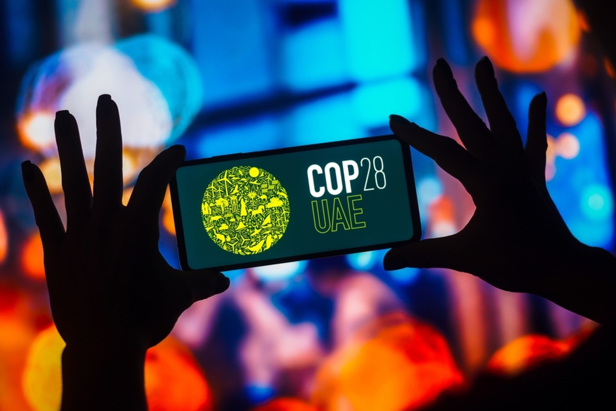 Smartphone displaying "COP28 UAE" with environmental icons.