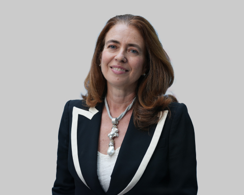 Woman with brown hair smiling in a black blazer with a silver necklace.