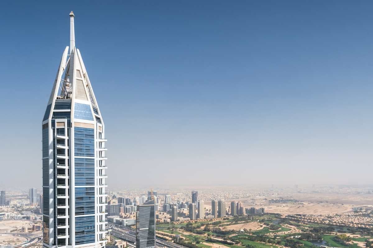 Slender skyscraper overlooking city and golf course.
