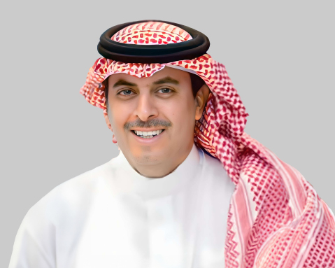 Man in thawb and keffiyeh smiles at the camera.