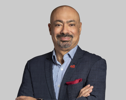 Bald man in a blue blazer stands with arms crossed.