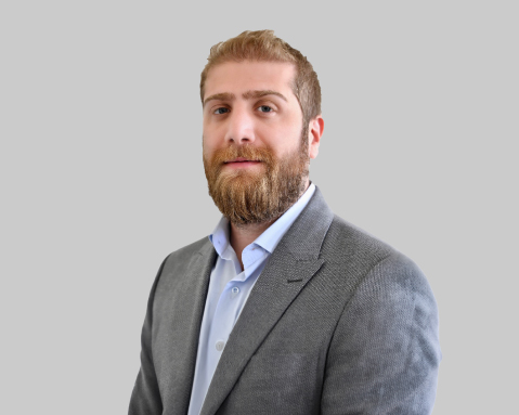 Man with a beard in a gray suit against a gray background.
