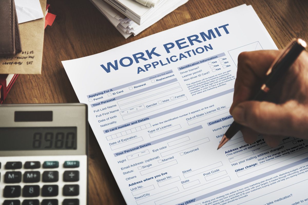 Work permit application being filled out with nearby documents.