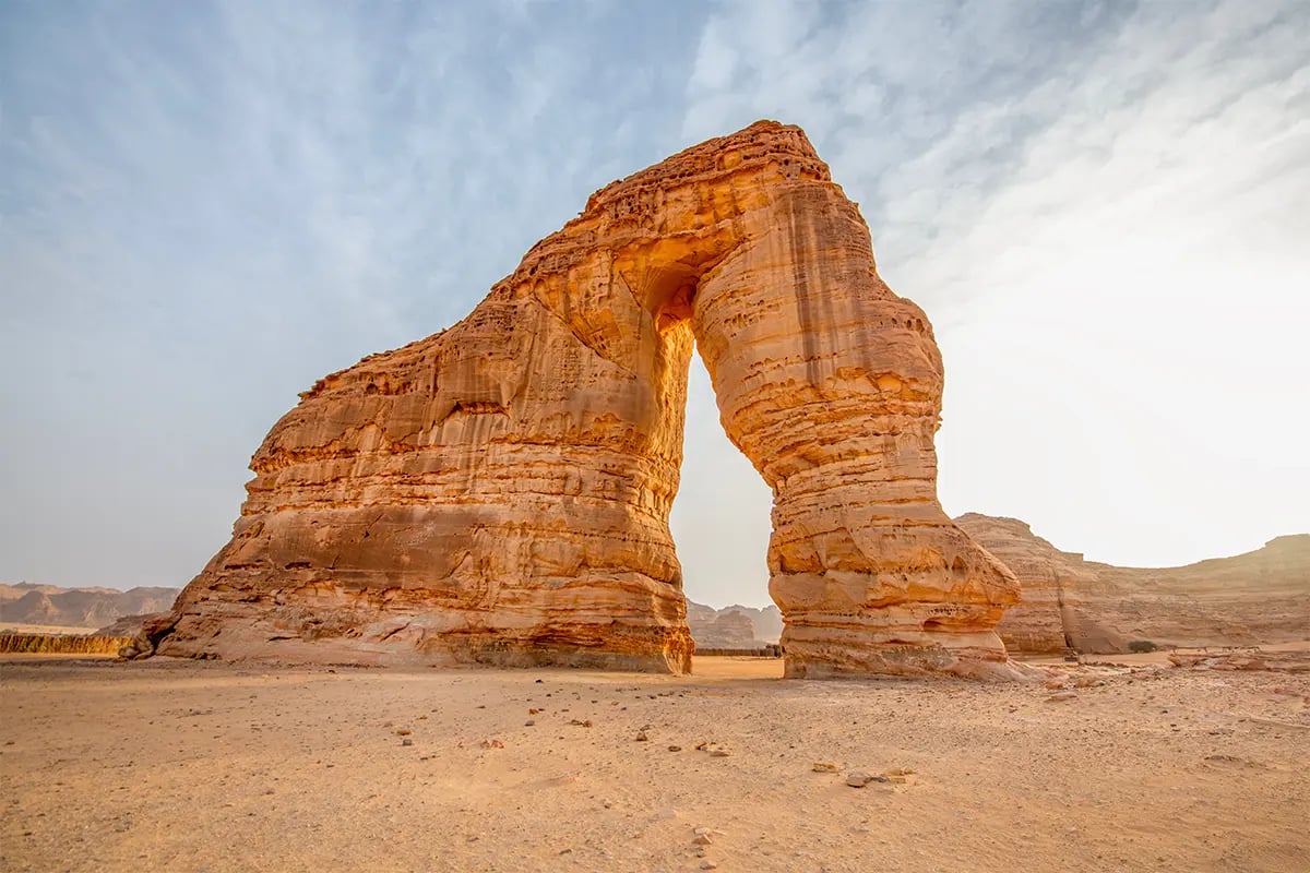 Sandstone rock arch in desert landscape.