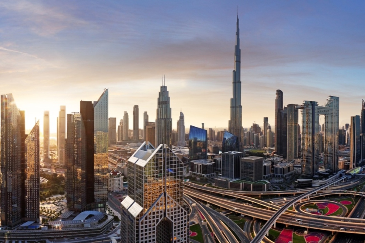 Sunset cityscape with prominent skyscrapers and highway interchanges.